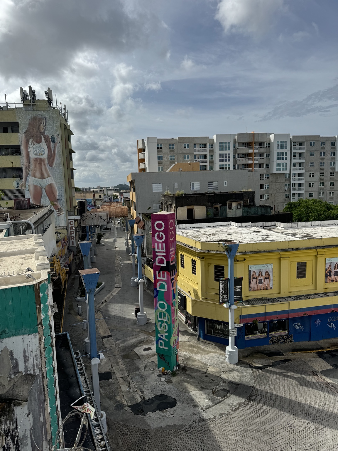 Vista de un entorno urbano con fachadas comerciales, paseo peatonal y edificios residenciales.